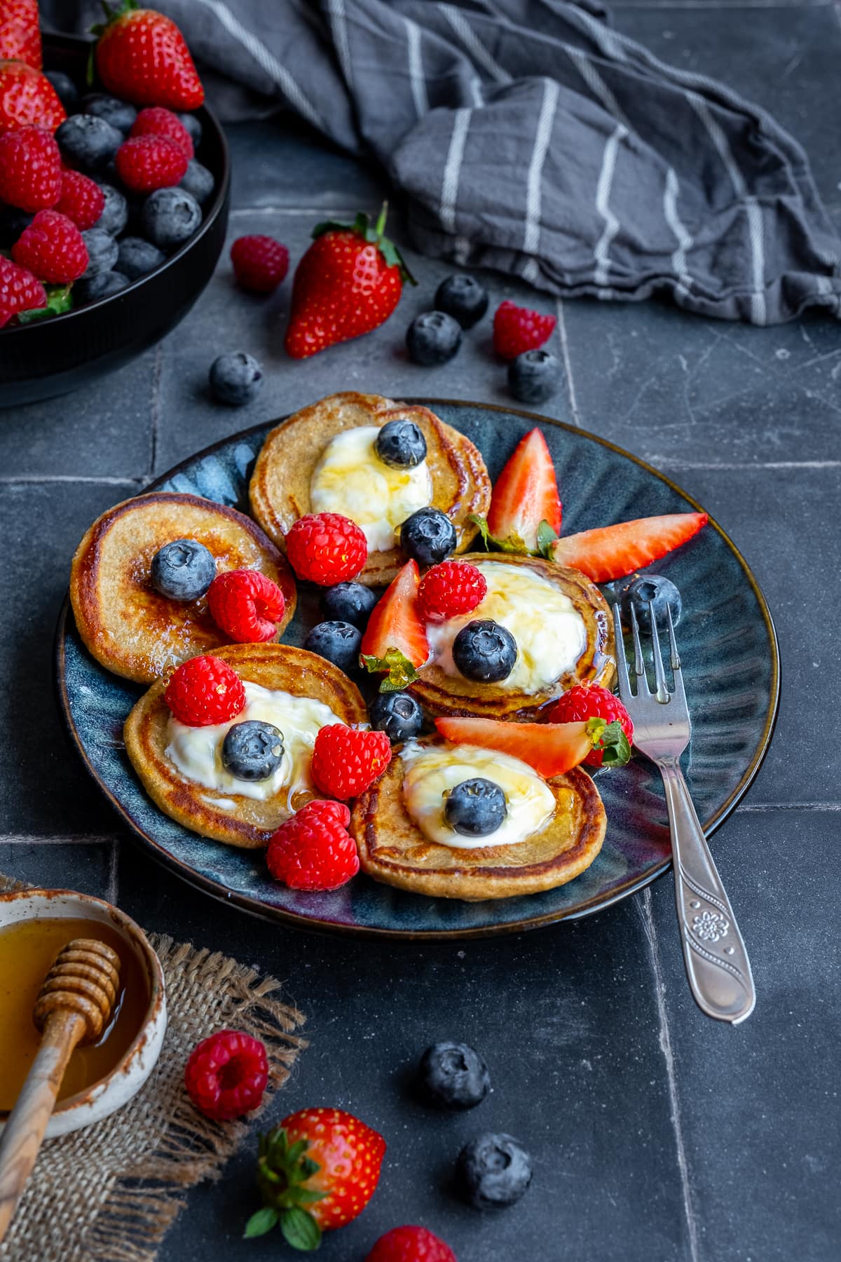 3 Ingredient Banana Oat Egg Pancakes on a plate with yogurt, honey and berries