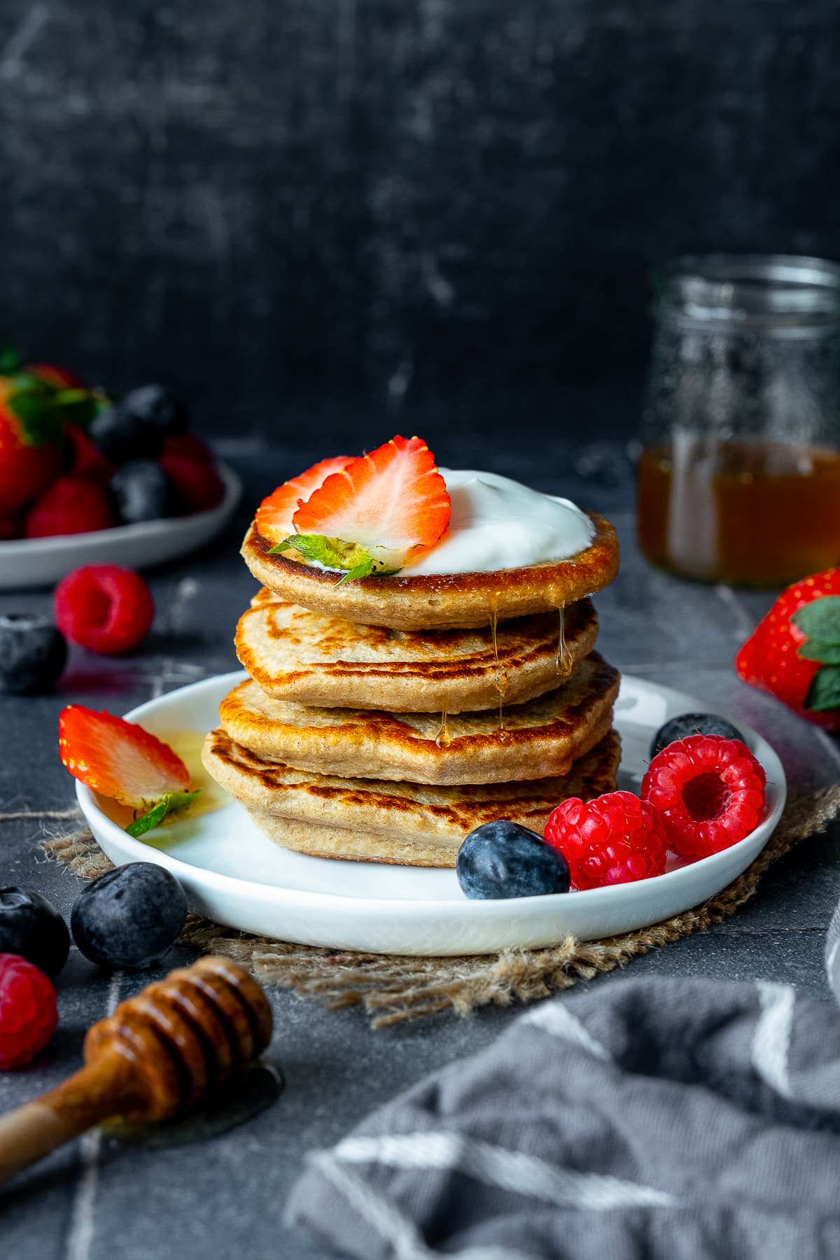 A stack of 4 Banana Oat Egg Pancakes with yogurt and berries