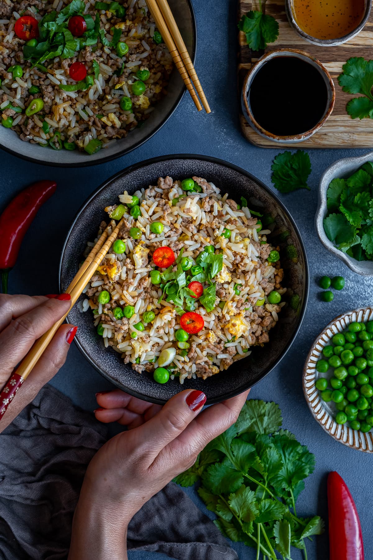 Overhead shot of Easy Beef Fried Rice in a bowl, with a woman's hands holding chopsticks