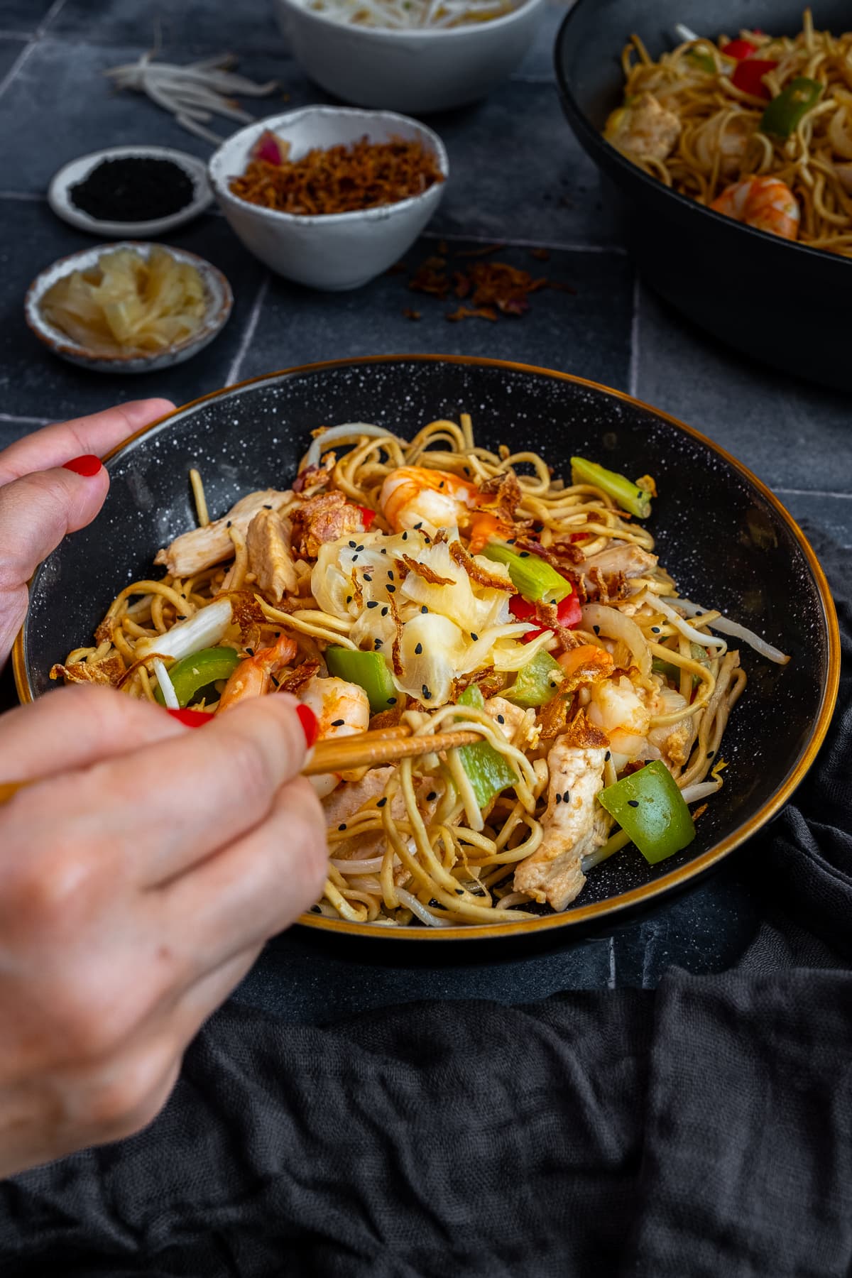 Chicken and Prawn Yaki Soba with chopsticks held by a woman's hands