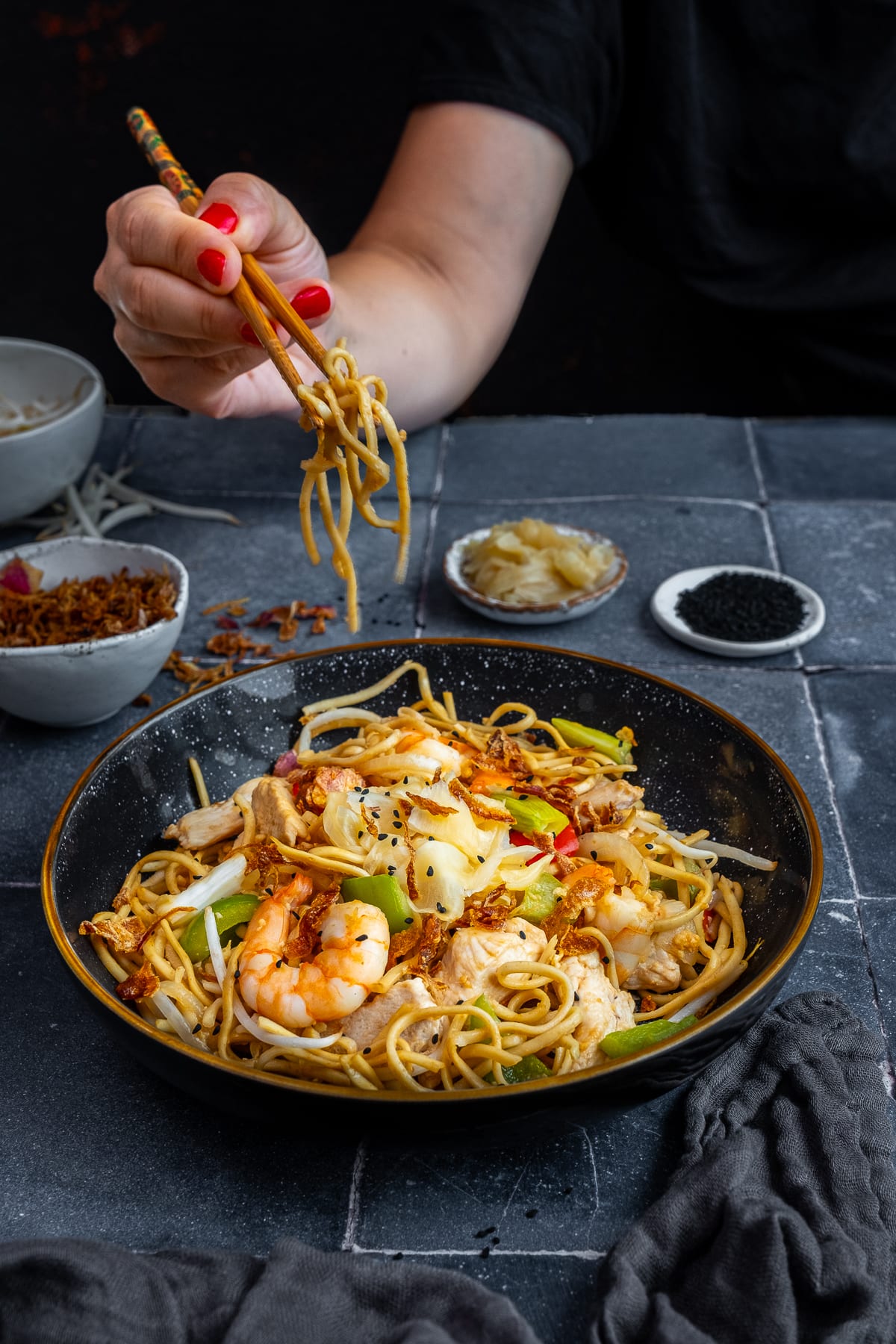 Chicken and Prawn Yaki Soba with chopsticks held by a woman's hands