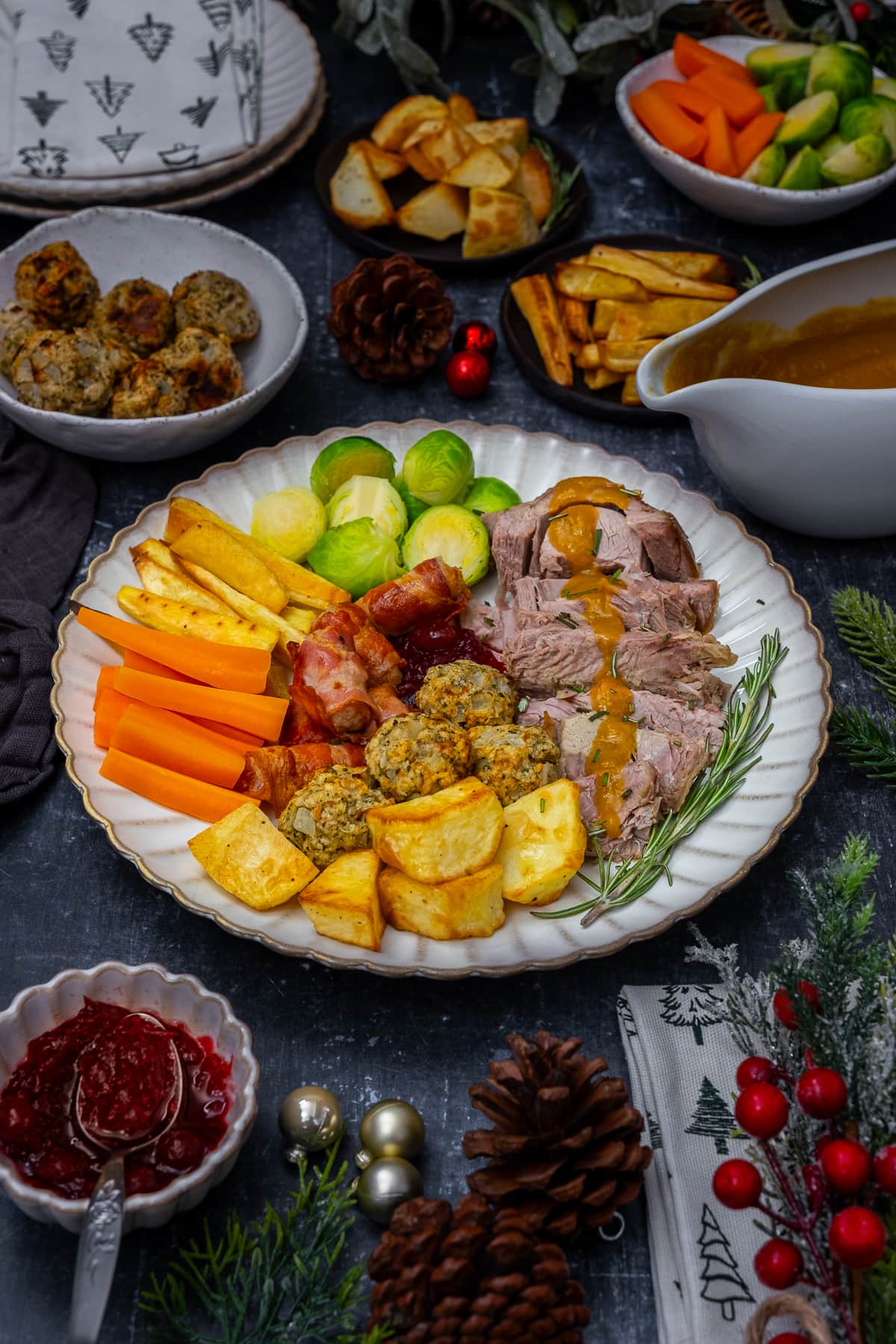 Plate filled with sliced turkey, sprouts, carrots, roast parsnips, roast potatoes, stuffing balls, cranberry sauce and gravy