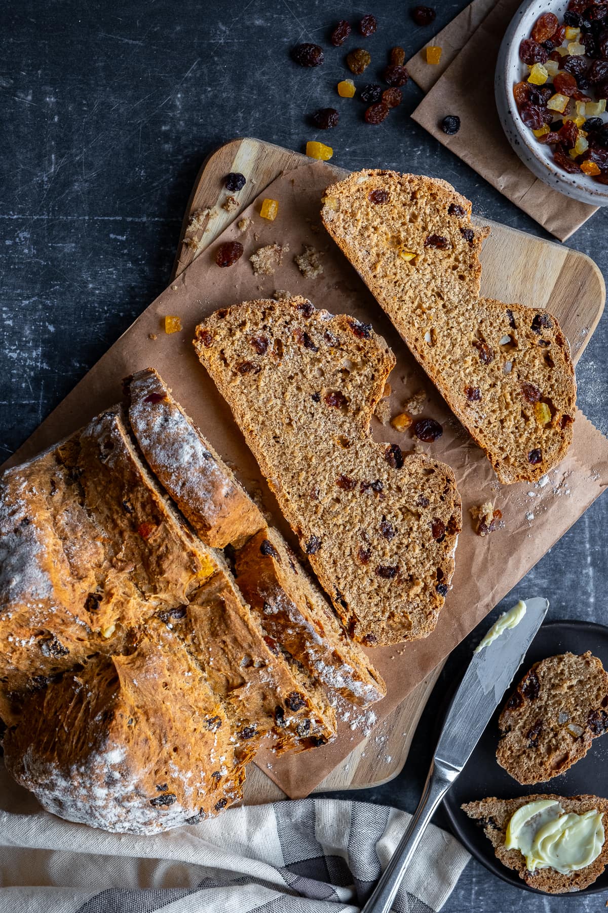 Overhead shot of a half-sliced loaf of Easy Fruit Soda Bread on a wooden board.