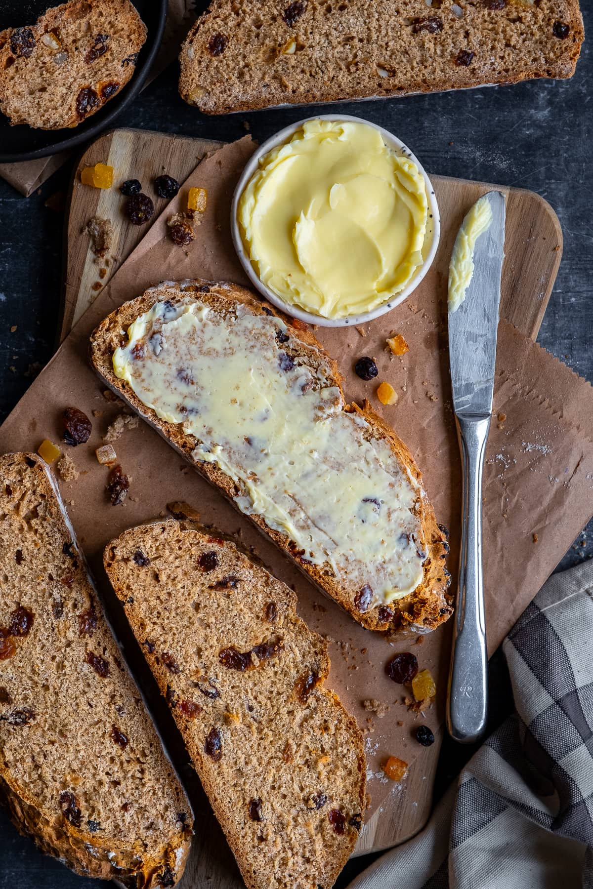 Slices of Easy Fruit Soda Bread - one slice is thickly spread with butter.