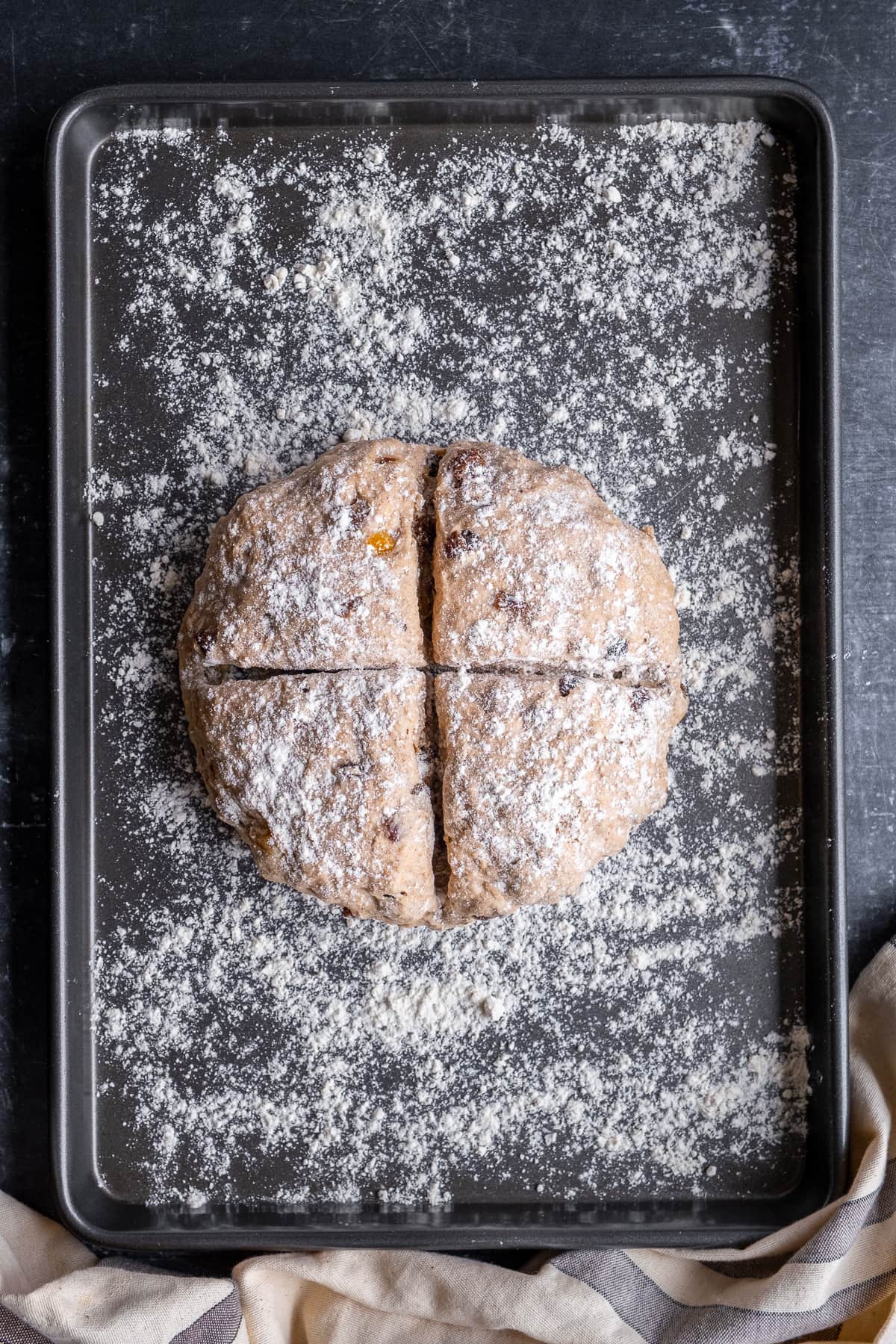 Uncooked loaf of Easy Fruit Soda Bread on a baking tray with a big deep cross cut in the dough.