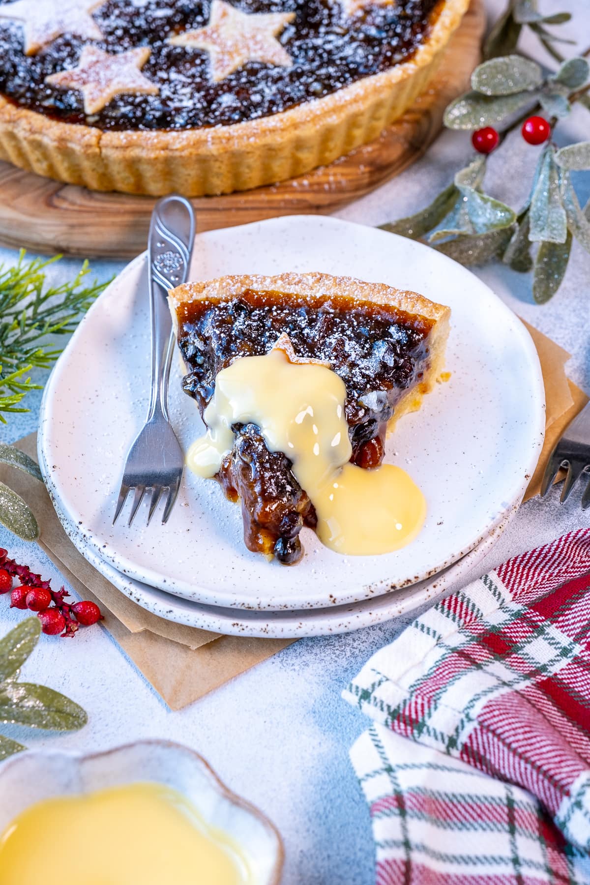 Closeup of 1 slice of easy mincemeat tart with a drizzle of custard on top