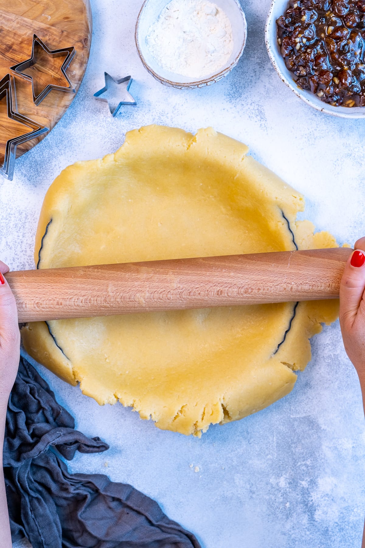 Trimming off pastry overhang by rolling a rolling pin over the top of the tart