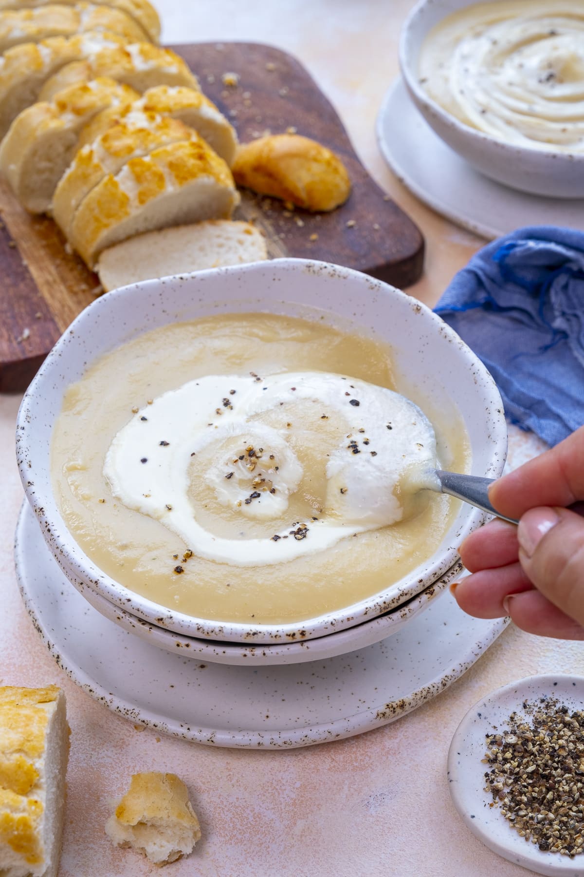 Easy Peasy Parsnip Soup in a bowl. A lady's hand is holding a spoon and taking a spoonful of the soup.