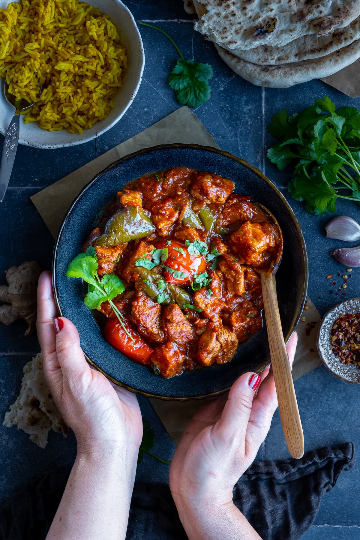 Overhead shot of Easy Peasy Pork Curry in a bowl. A woman's hands are holding the bowl.