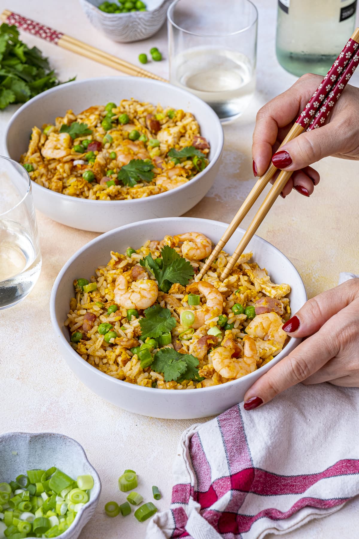 Easy Peasy Special Fried Rice in two bowls. A woman's hands are holding chopsticks about to pick up some of the rice