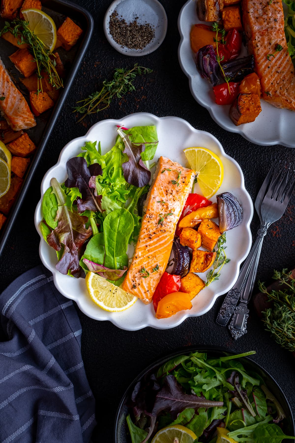 Overhead shot of One cooked salmon fillet on a plate with roasted vegetable and salad leaves