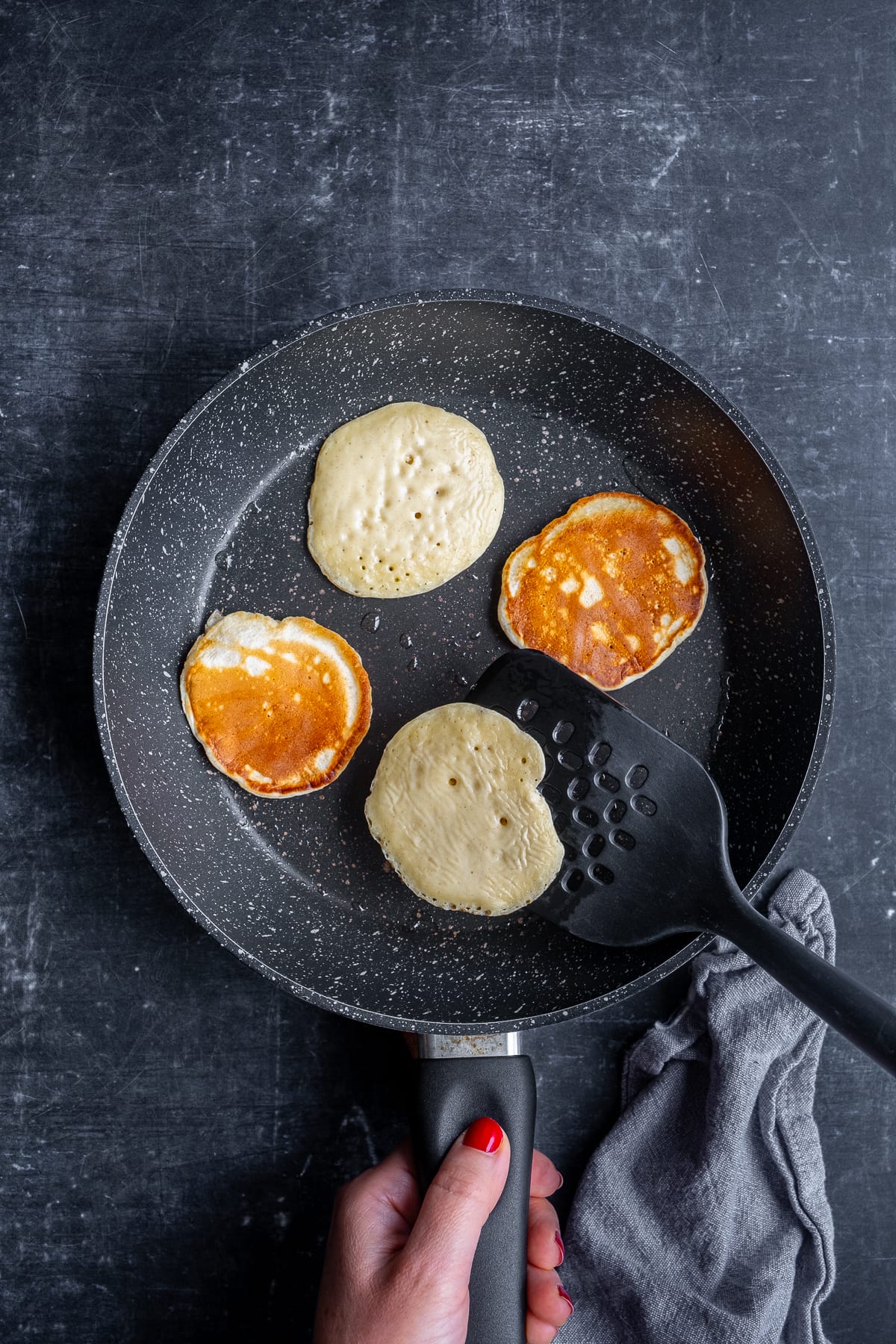 Scotch pancakes in the frying pan. Two turned over, two not.