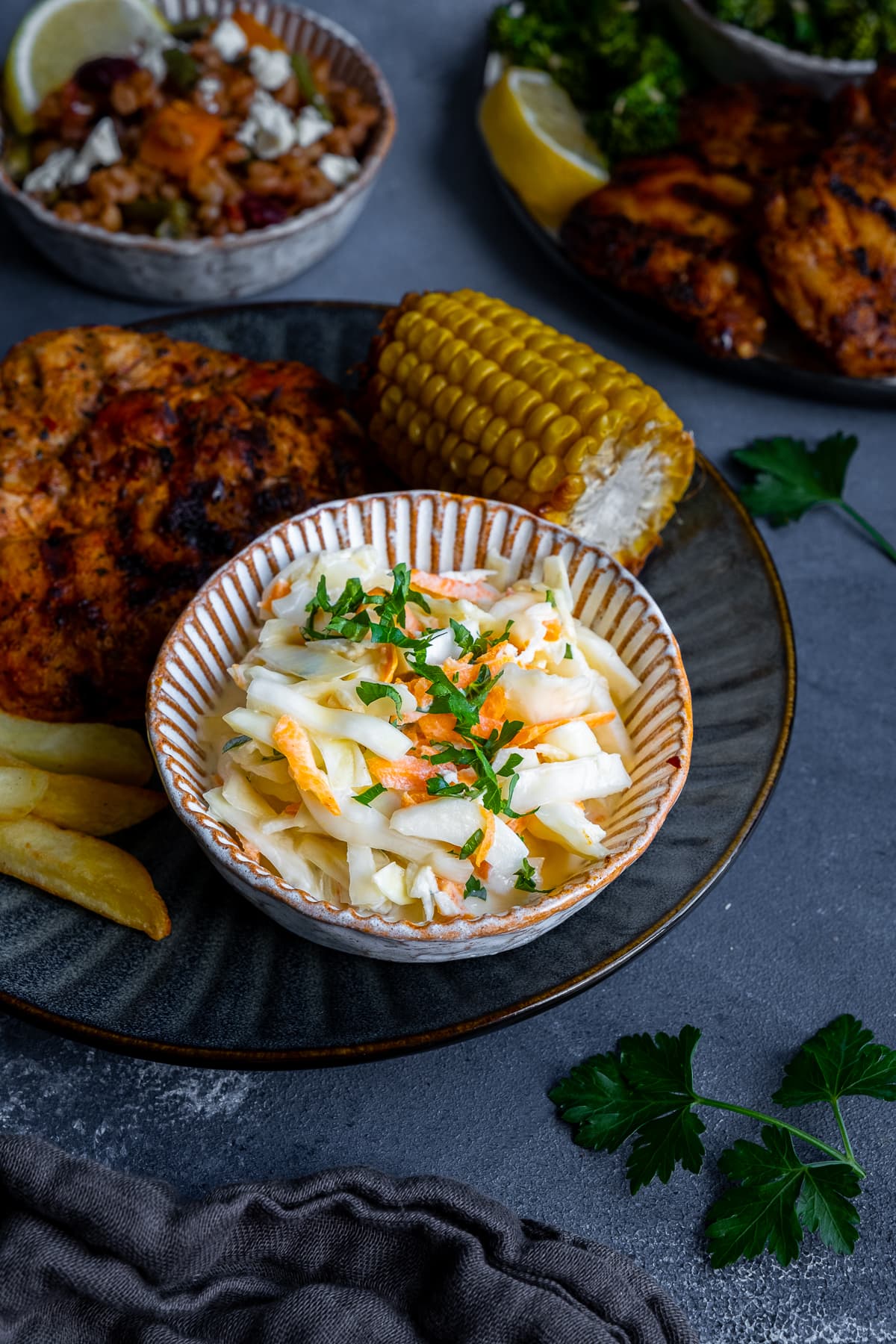 Homemade Nando’s Coleslaw on a plate with butterfly chicken, corn on the cob and chips