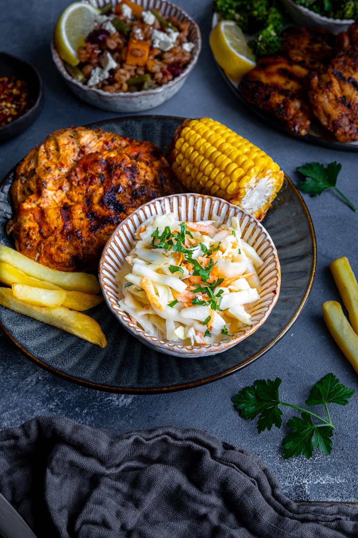 Homemade Nando’s Coleslaw on a plate with butterfly chicken, corn on the cob and chips