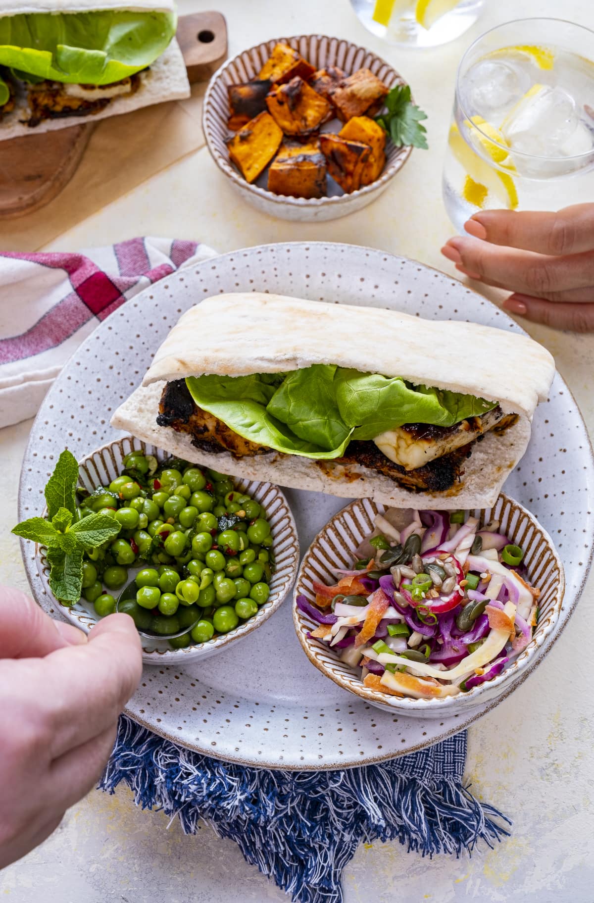 Homemade Nando's Fino Pitta on a plate with bowls of macho peas and rainbow slaw