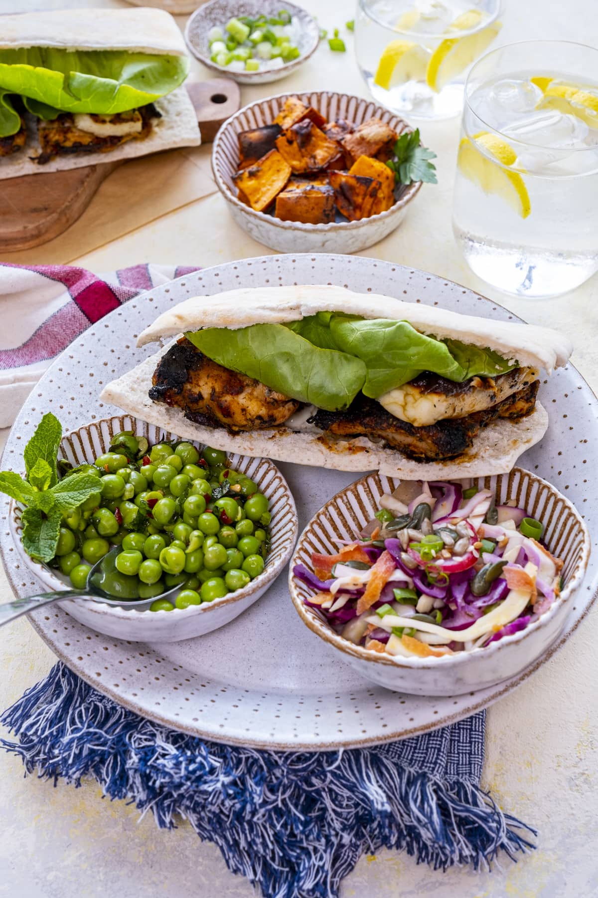 Homemade Nando's Fino Pitta on a plate with bowls of macho peas and rainbow slaw