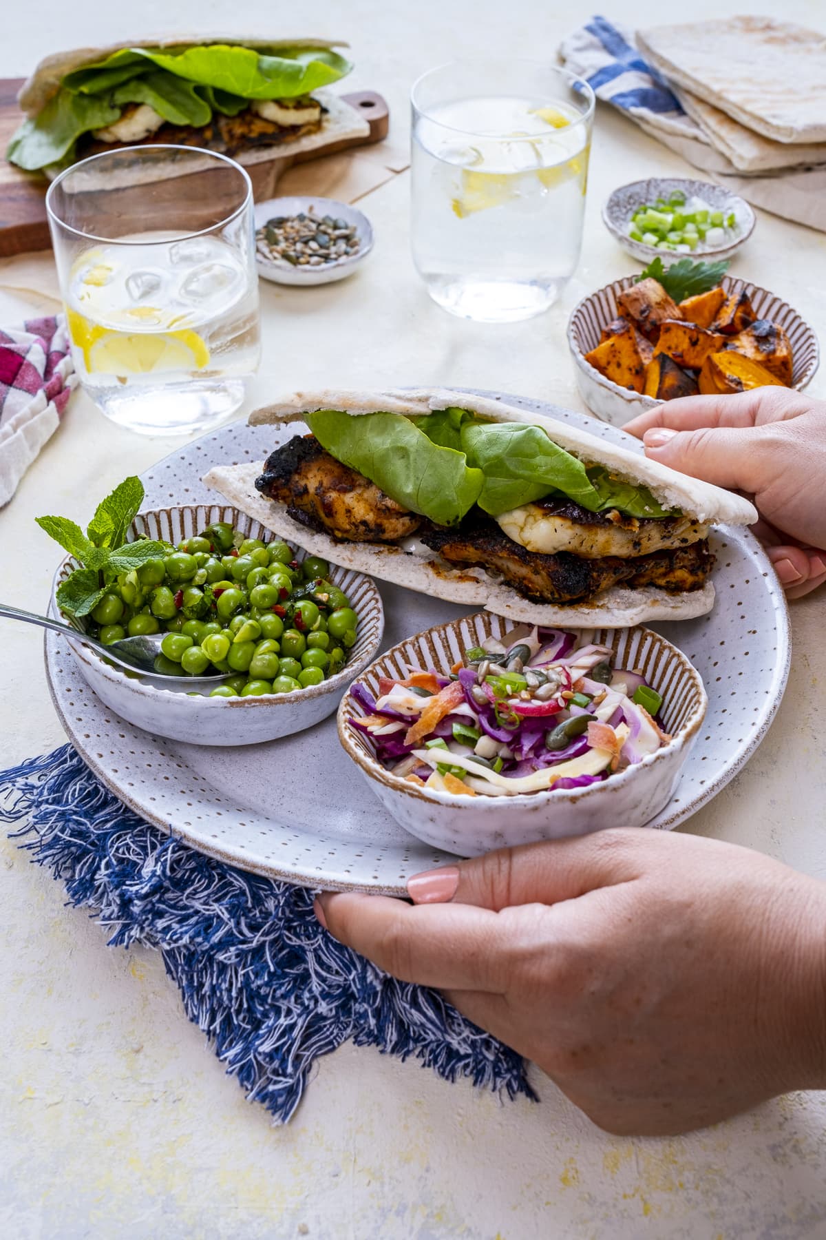 Homemade Nando's Fino Pitta on a plate with bowls of macho peas and rainbow slaw