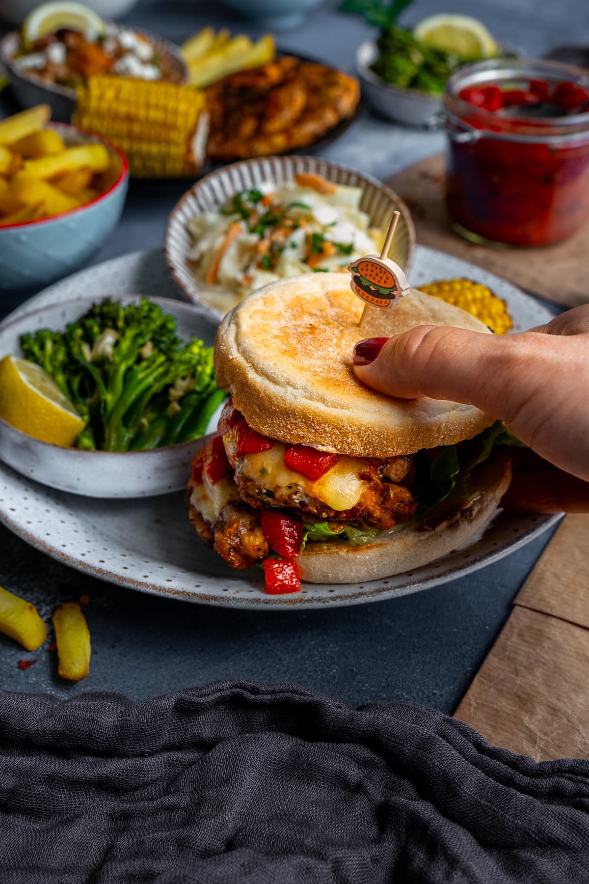 Closeup of Homemade Nandos Sunset Burgers with a woman's hands holding the burger as if just about to pick it up