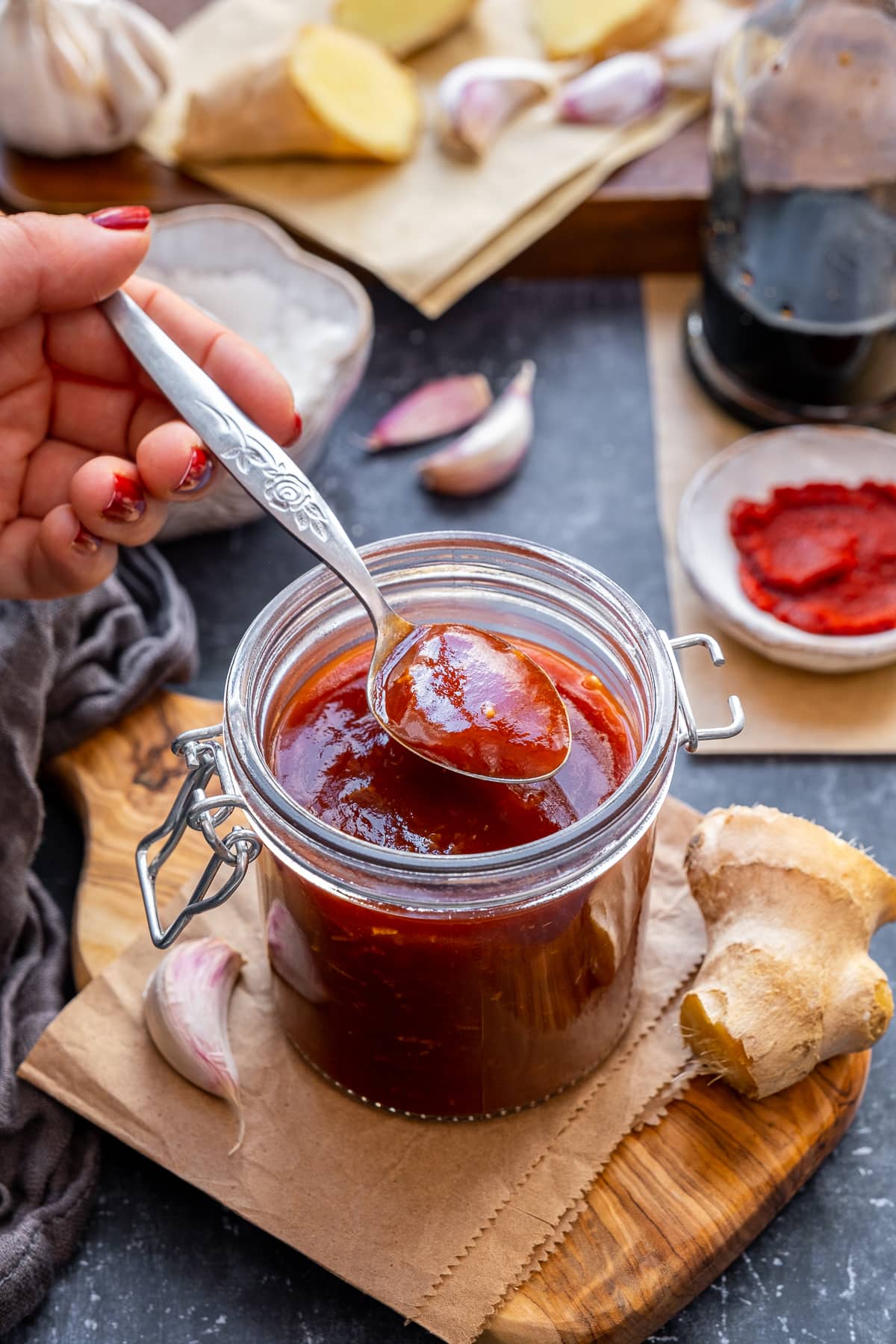 Woman's hand holding a spoon, taking a spoonful of sweet and sour sauce