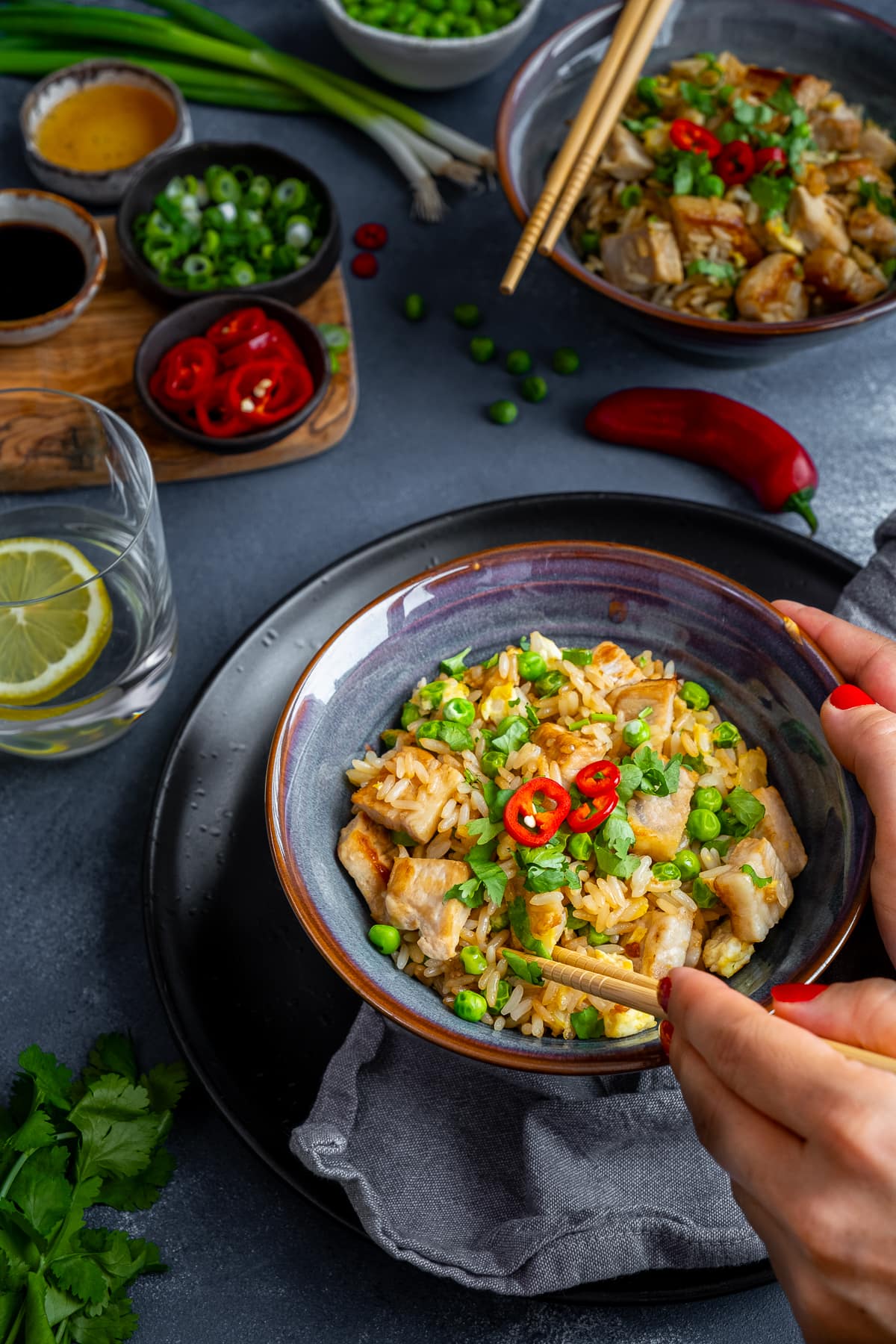 Leftover Pork Fried Rice in a bowl, with chopsticks held by a woman's hands