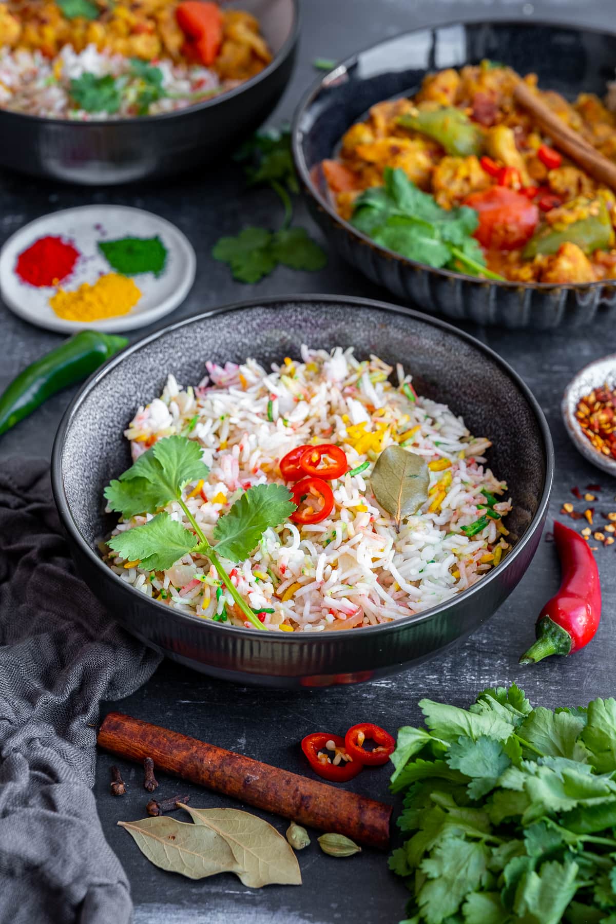 Multicoloured Pilau Rice in a bowl with chicken dhansak in the background