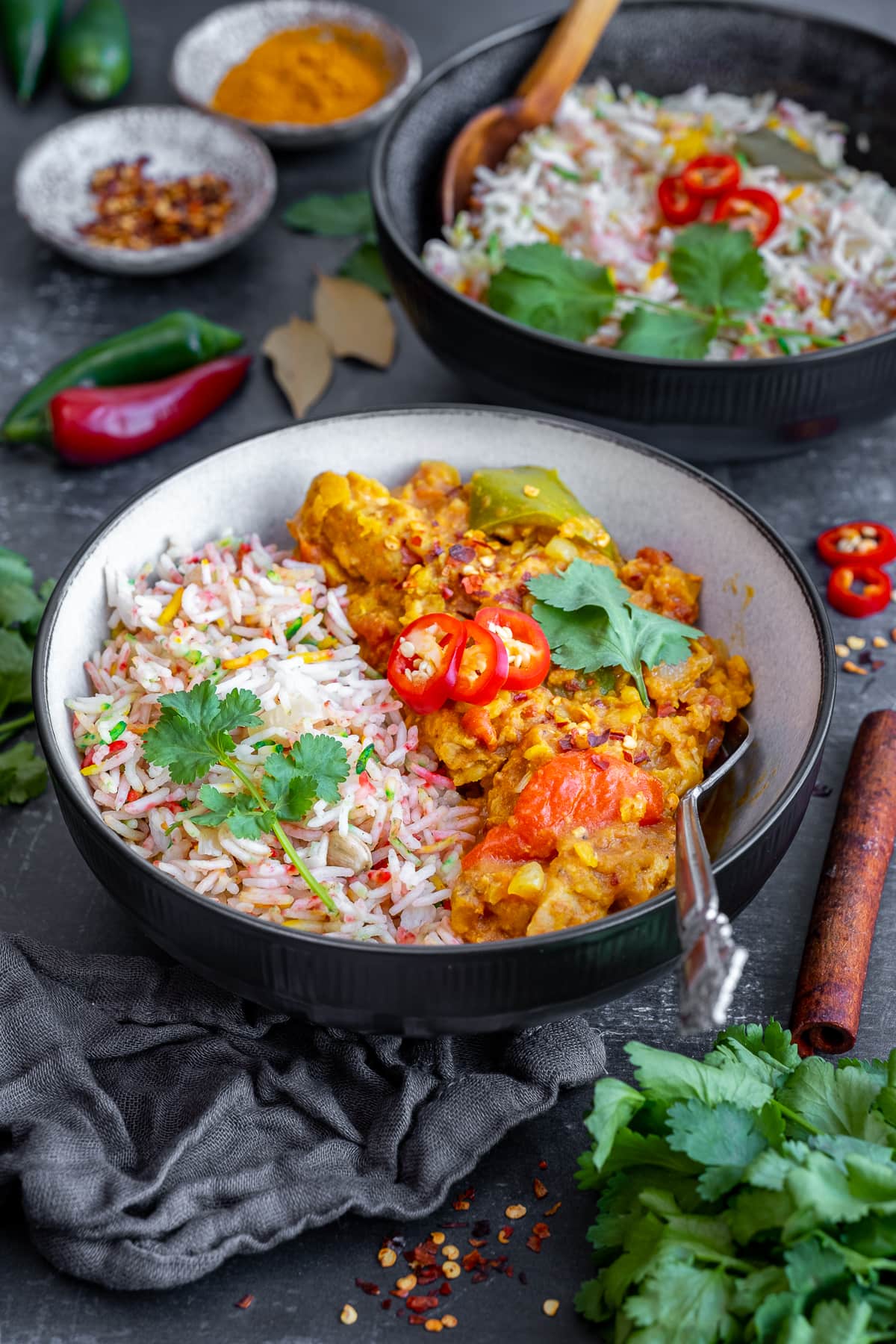 Multicoloured Pilau Rice in a bowl with chicken dhansak