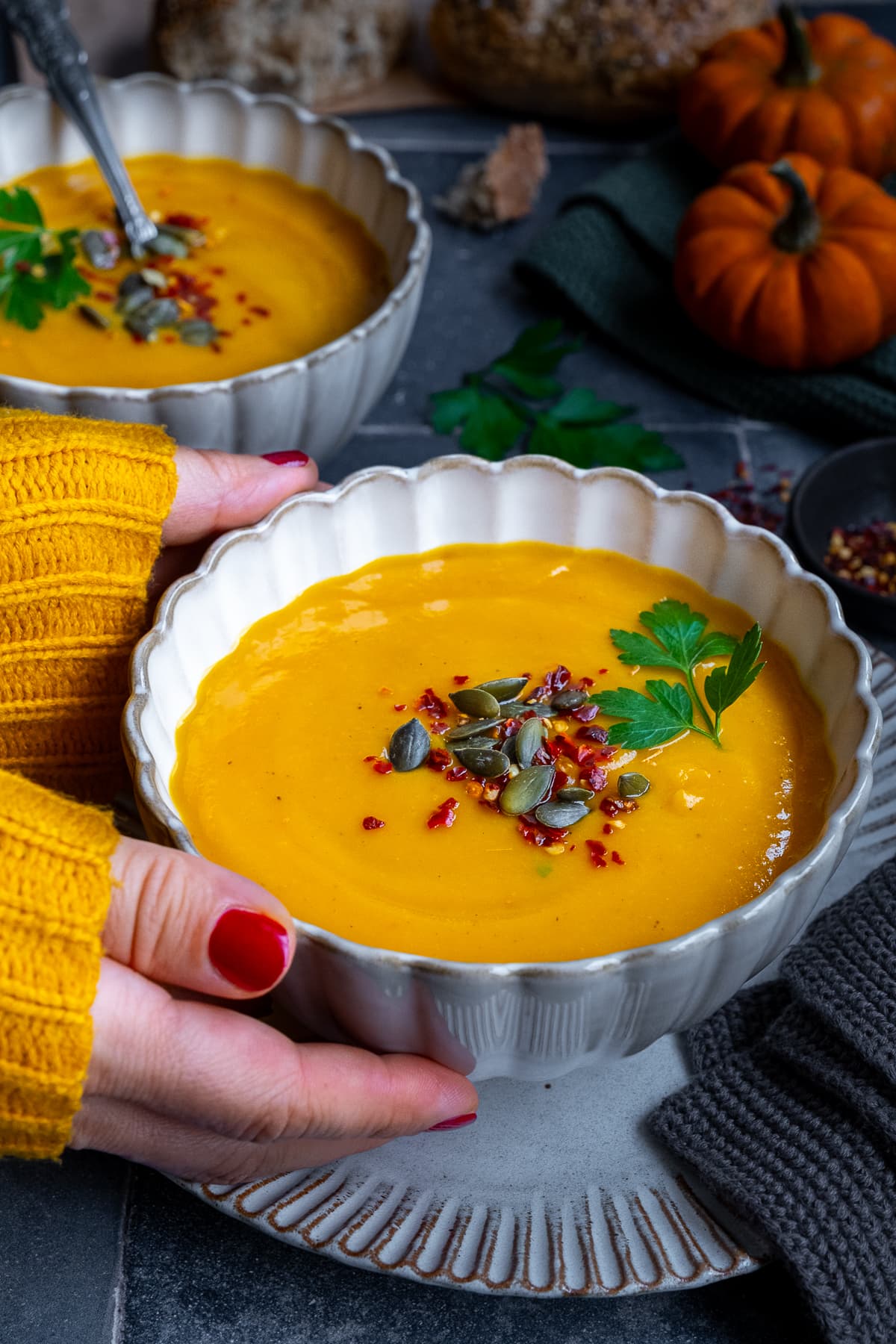 Closeup of Pumpkin and Sweet Potato Soup. A woman's hands are holding the bowl.