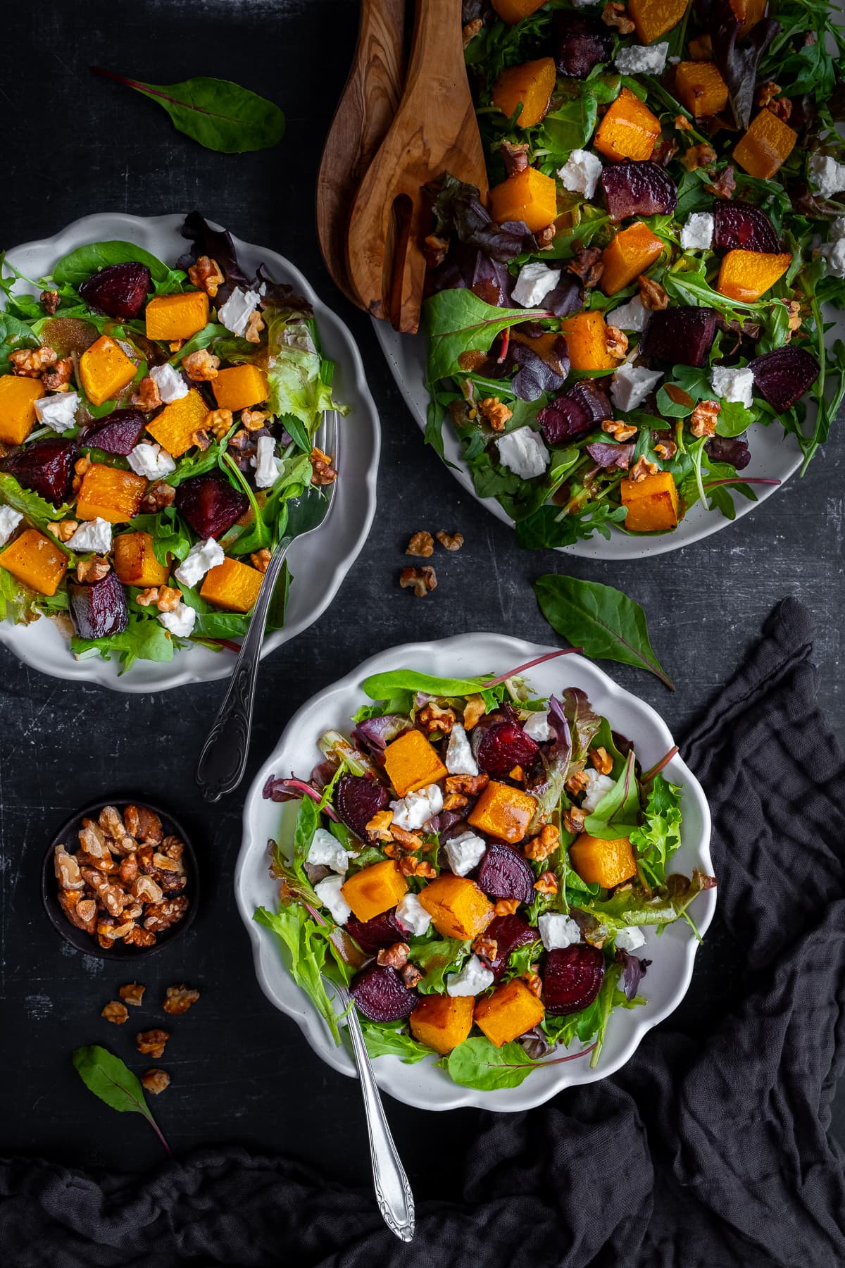 Overhead shot of Roasted Butternut Squash and Beetroot Salad with Feta and Walnuts in a serving dish and two bowls.