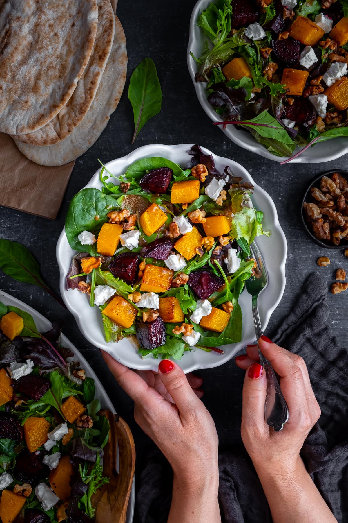 Overhead shot of Roasted Butternut Squash and Beetroot Salad with Feta and Walnuts in a white bowl with pittas