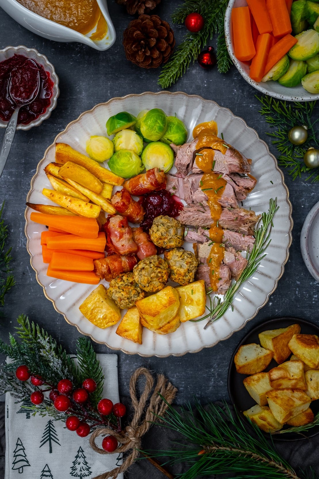 Plate filled with sliced turkey, sprouts, carrots, roast parsnips, roast potatoes, stuffing balls, cranberry sauce and gravy