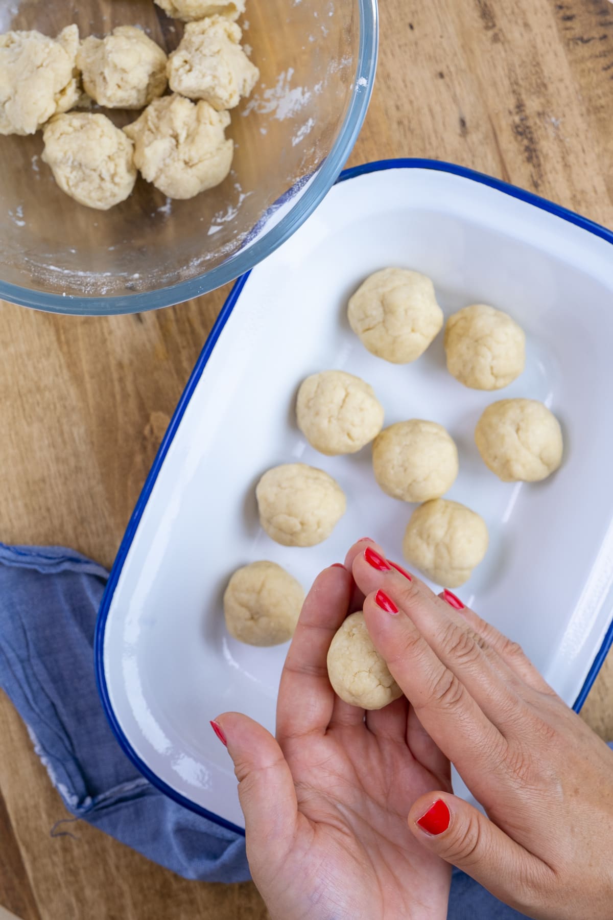 Raw suet dumplings being shaped by a pair of female hands