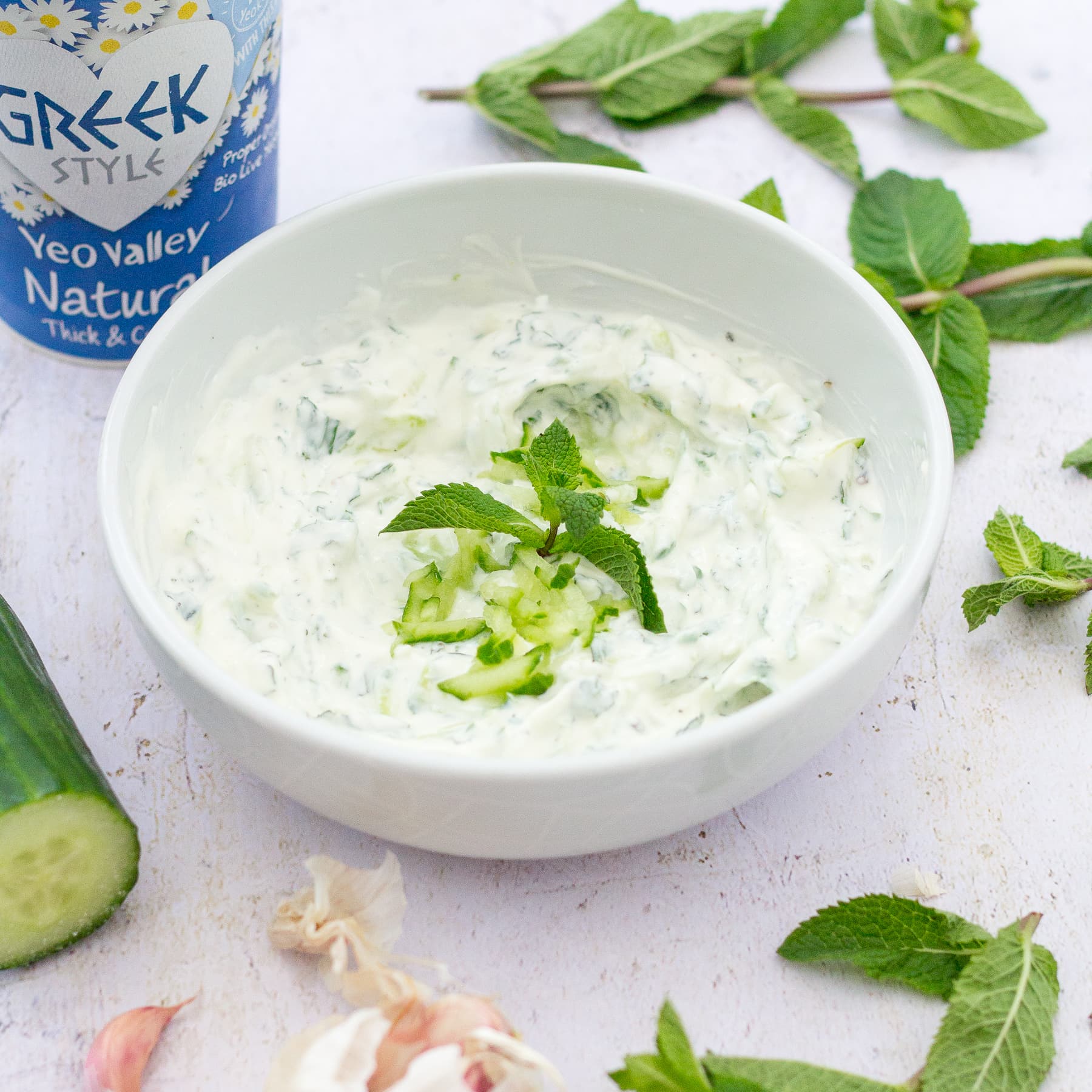 Easy Peasy Tzatziki in a bowl with ingredients surrounding it